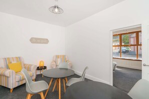 A room with striped sofas, a round table, and a 'Be our guest' sign. - THE SPACE Large House In Afan Forest Bike Park (Port Talbot)