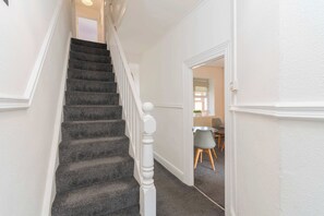 A staircase with a white balustrade leading to a room with a dining area.
