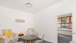 A room with striped sofas, a round table, and a sign that says "Be our guest". - THE SPACE Large House In Afan Forest Bike Park (Port Talbot)