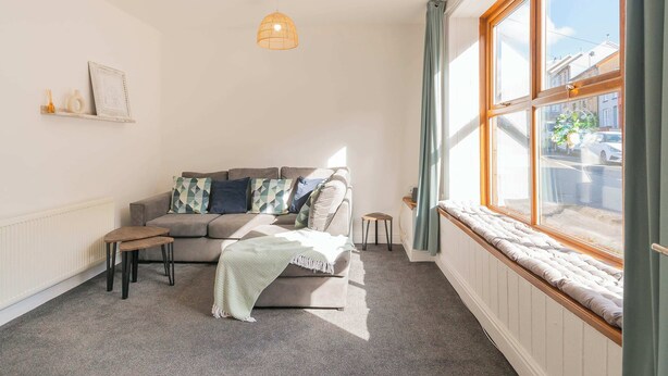 A cozy living room with a sofa, a small table, and a window with curtains. - THE SPACE Large House In Afan Forest Bike Park (Port Talbot)