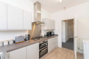 Een kleine keuken met een gasfornuis, oven en een broodrooster op het aanrecht.