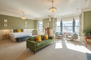 A spacious room with a large bed, a green sofa, and multiple seating areas. - Host & Stay | Sandpiper (Saltburn-by-the-Sea)