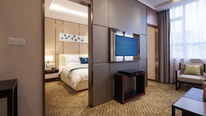 Ein Hotelzimmer mit Bett, Fernseher, Schreibtisch und Stuhl.