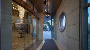 Ein moderner Hotelkorridor mit Glastür, rundem Fenster und einer Chandelierleuchtre.