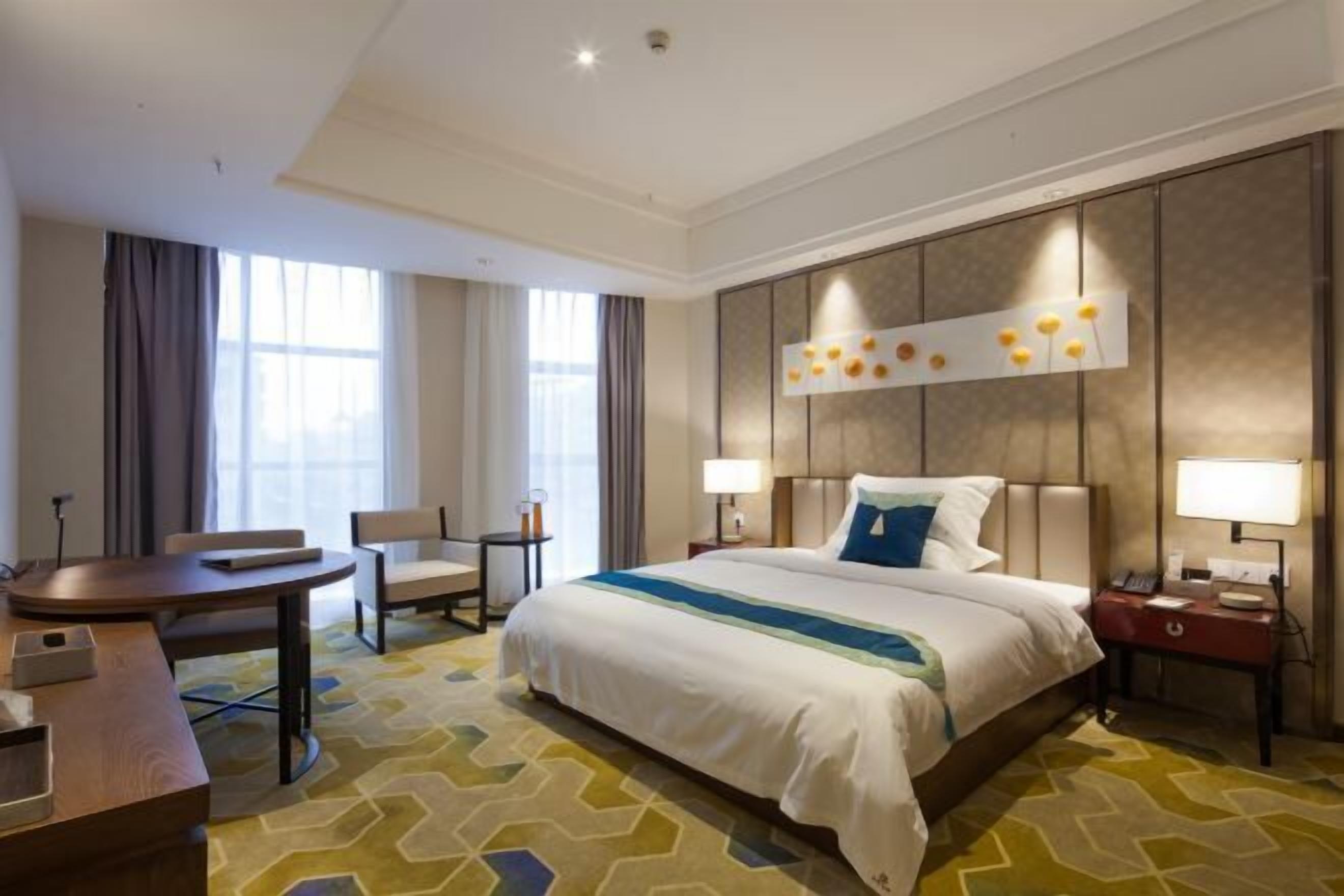 Ein Hotelzimmer mit einem großen Bett, einem Schreibtisch, einem Stuhl und einem Nachttisch mit Lampe.