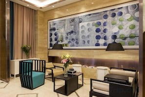 Un vestíbulo moderno con un cuadro abstracto grande, disposición de asientos y un mostrador de recepción.