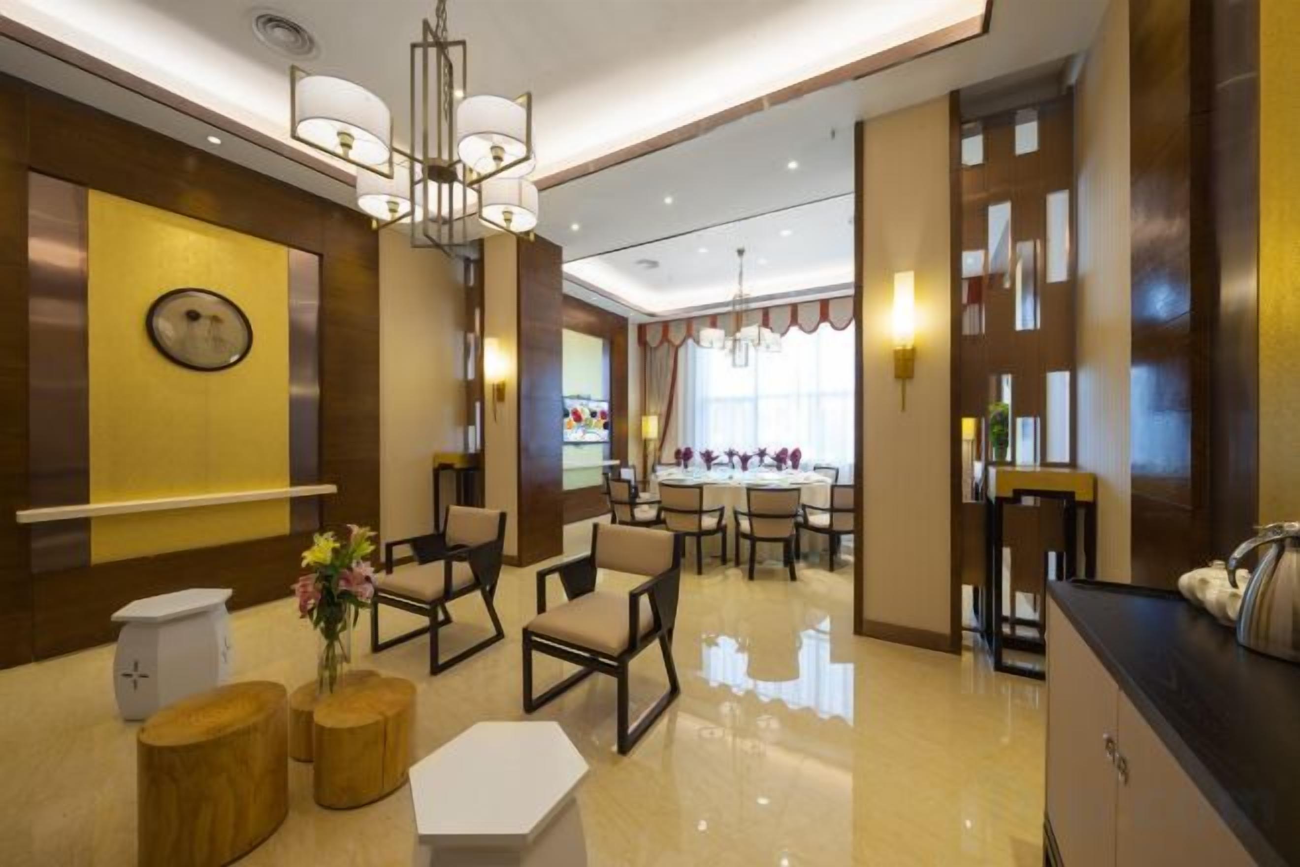 A hotel lobby with a reception desk, seating area, and a large window.