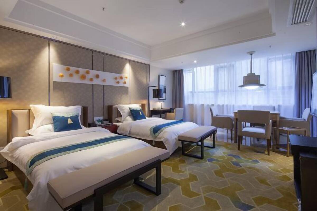 Hotellihuone, jossa on kaksi sänkyä, työpöytä ja tuoli.