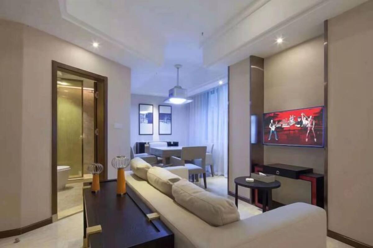 Moderni hotellihuone, jossa on sohva, televisio, ruokailutila ja kylpyhuone.