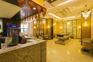 Un vestíbulo de hotel con mostrador de recepción, zona de estar y un candelabro.