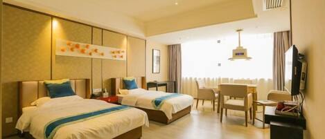 Quarto de hotel com duas camas, uma escrivaninha, uma cadeira e uma televisão.