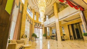 A spacious lobby with a high ceiling, chandeliers, and a modern design.