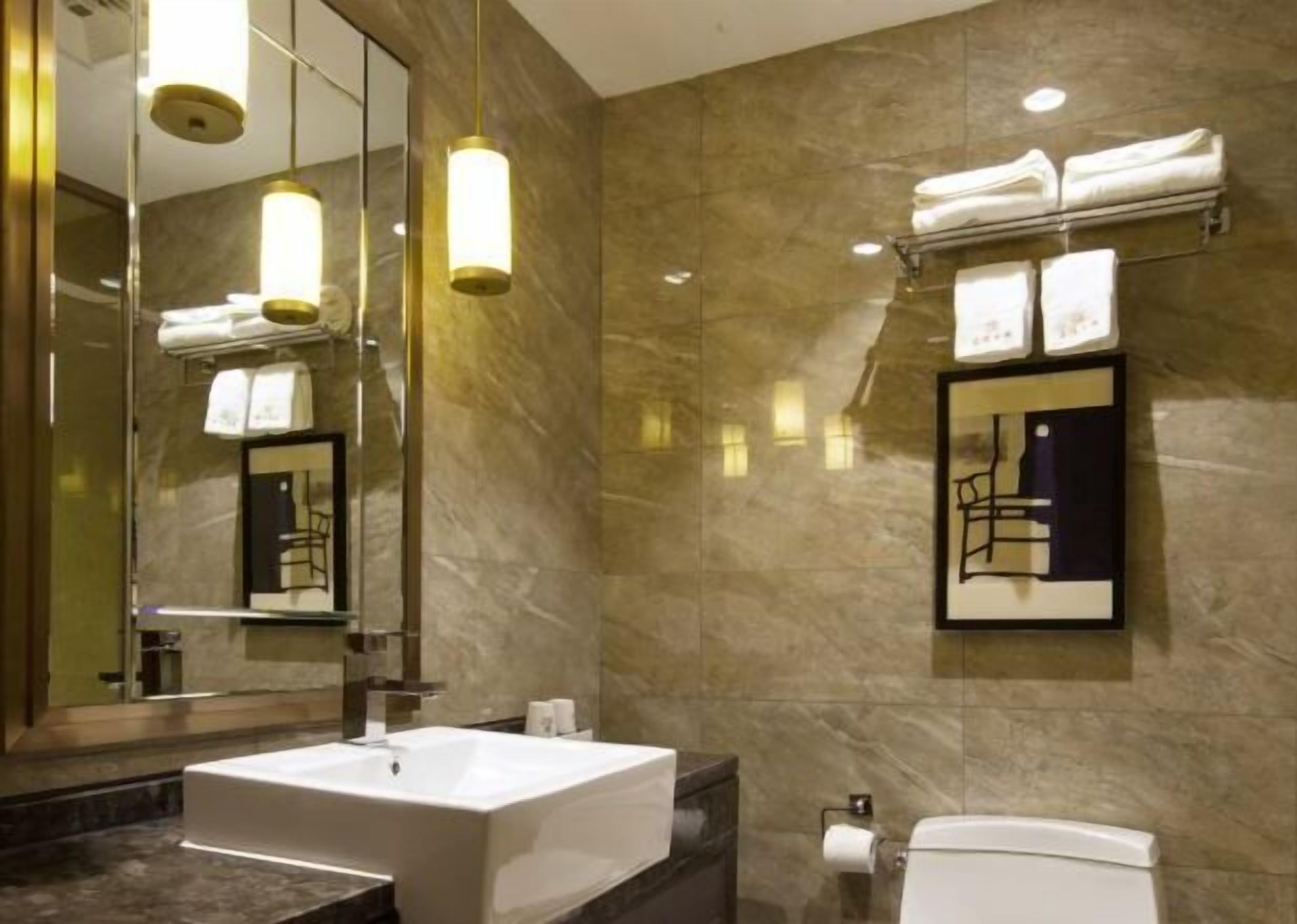 Ein modernes Badezimmer mit einem großen Spiegel, einem freistehenden Waschbecken, einer Toilette und einem Handtuchhalter mit Handtüchern.
