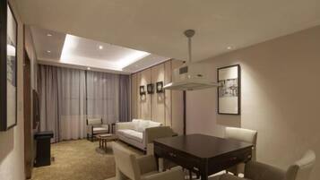 A modern hotel room with a dining area, a sofa, a small table, and a ceiling light.