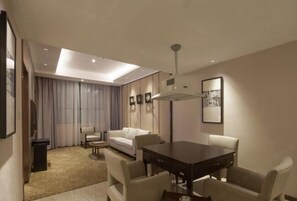 A modern hotel room with a dining area, a sofa, a small table, and a ceiling light.