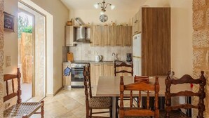 A kitchen with wooden cabinets, a dining table with chairs, a chandelier, and a view of the outdoors.