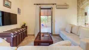 A living room with a sofa, a wooden coffee table, a TV, and a set of trunks.