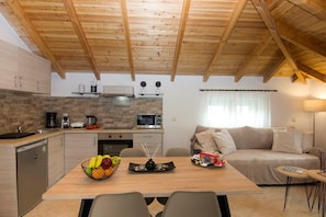 Eine moderne Küche mit Holzbalken, einer Stein-Spritzschutzleiste und einem Essbereich mit Tisch für zwei Personen.