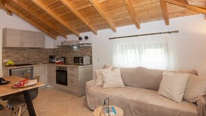 A compact kitchen with wooden cabinets, a dining table, and a sofa in a cozy living area.