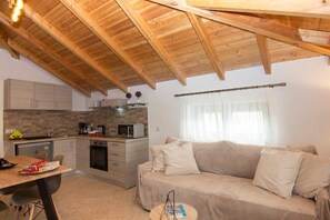 Een kleine keuken met houten kastjes, een eettafel en een bank in een gezellige woonruimte.