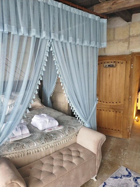 A bedroom with a bed covered by a sheer canopy, a wooden door labeled "MOZA", and a plush sofa. - Cappadocia Alaz Cave Otel (Nevsehir)