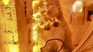 A cozy room with a stone wall, a patterned sofa, and a chair. - Cappadocia Alaz Cave Otel (Nevsehir)