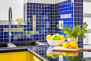 A kitchen with a sink, a bowl of fruit, a potted plant, and a cutting board. - Manella On Kloof (Cape Town)