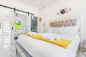 A modern bedroom with a large bed, a sliding door to a balcony, and a decorative wall piece.