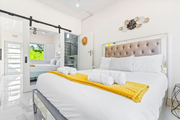 A modern bedroom with a large bed, a sliding door leading to a balcony, and a decorative wall piece. - Manella On Kloof (Cape Town)
