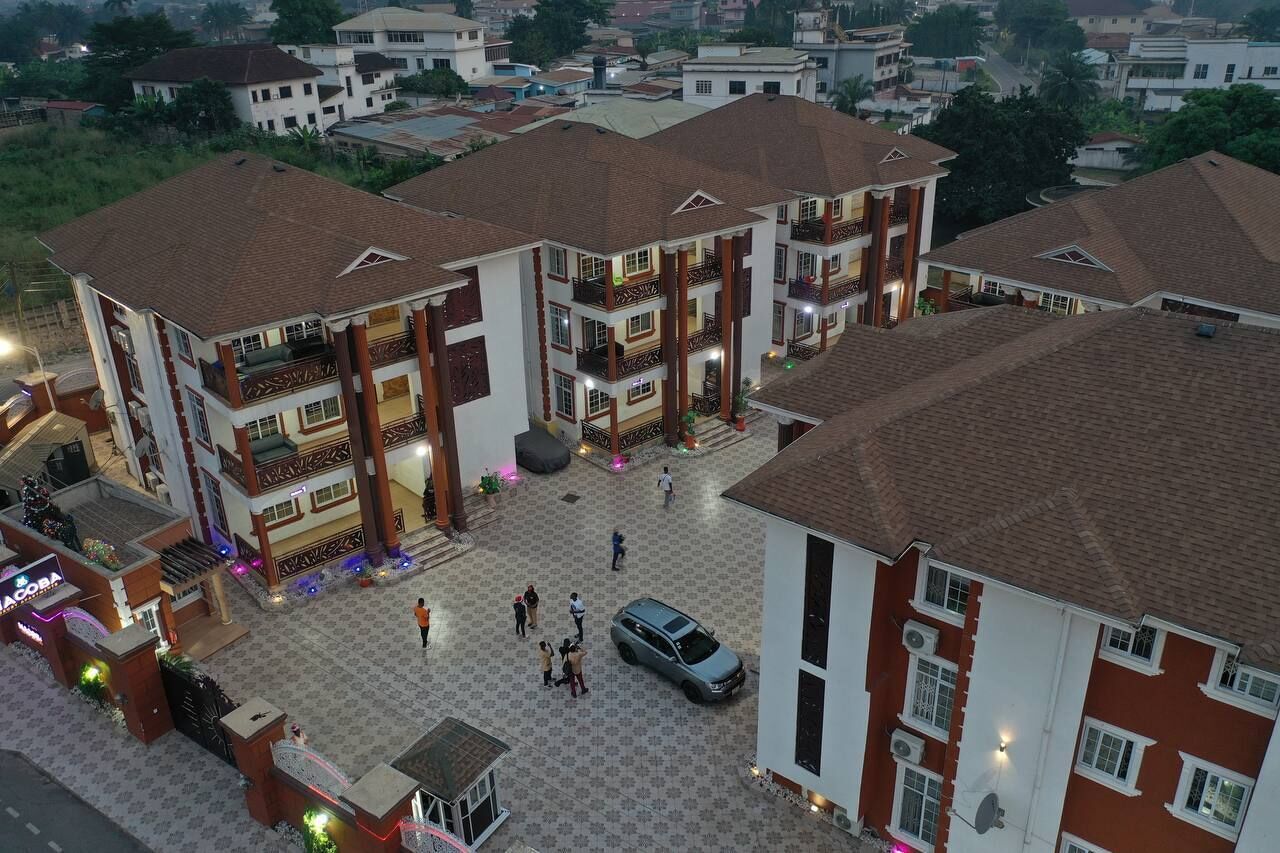Un immeuble résidentiel à plusieurs étages, doté de balcons, d’une cour intérieure et d’un espace de stationnement.