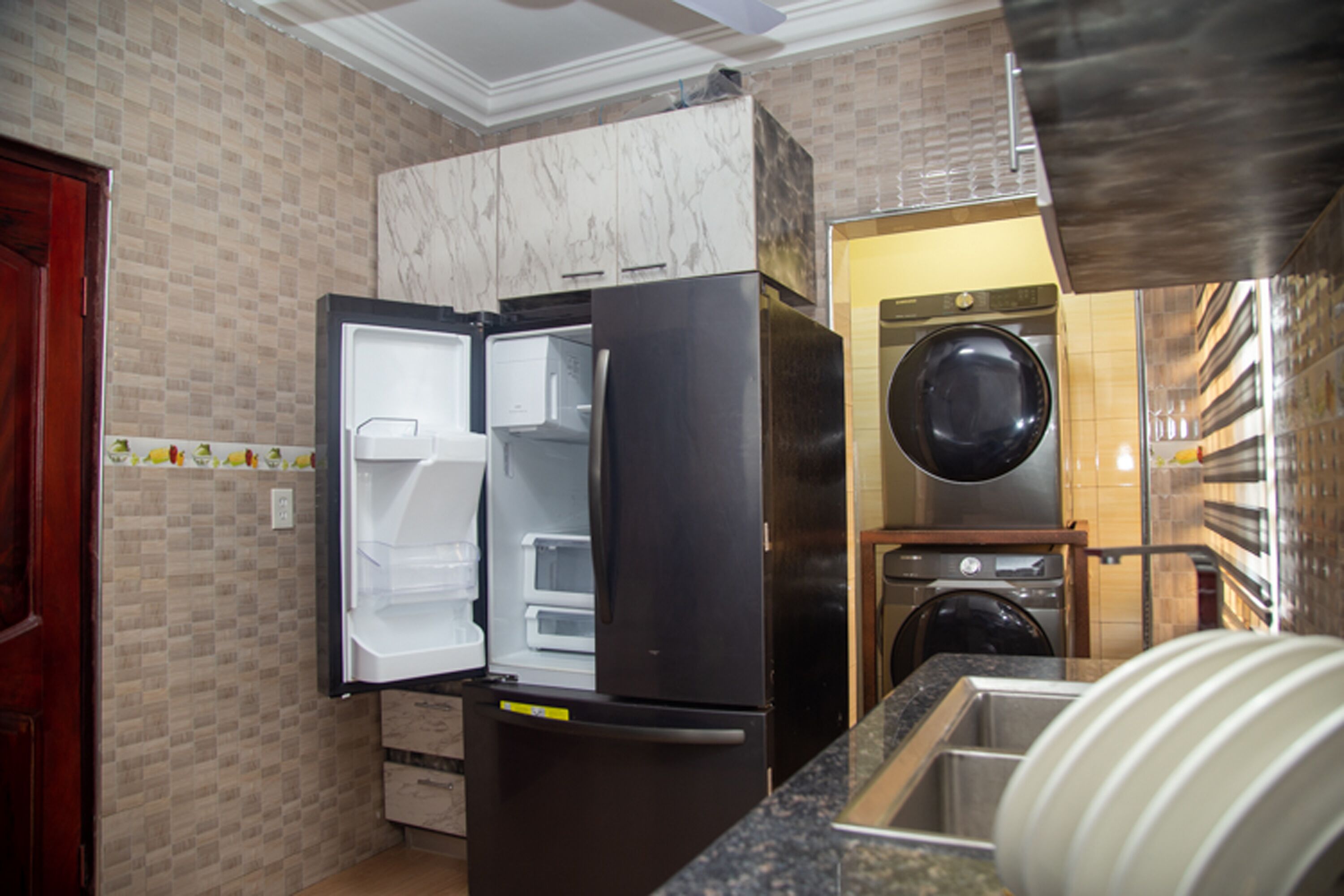 A compact kitchen with a built-in refrigerator, a microwave, and a washing machine.