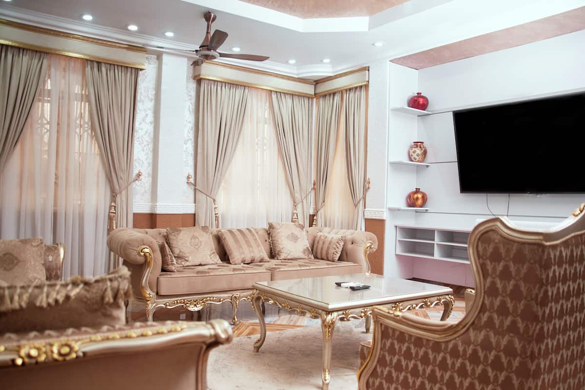 Un salón lujoso con un sofá beige, una mesa de centro ornamentada y sillones clásicos.