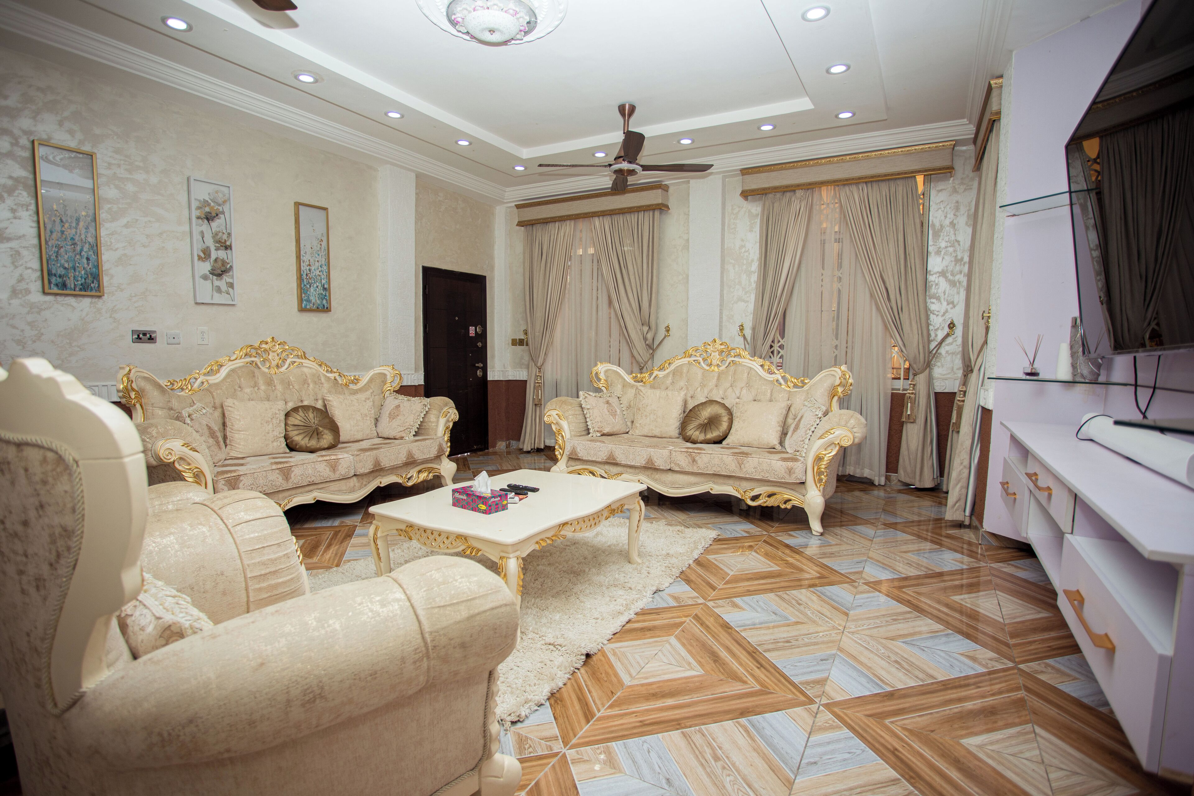 A spacious living room with ornate sofas, a coffee table, and a ceiling fan.
