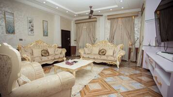 A spacious living room with ornate sofas, a coffee table, and a ceiling fan.