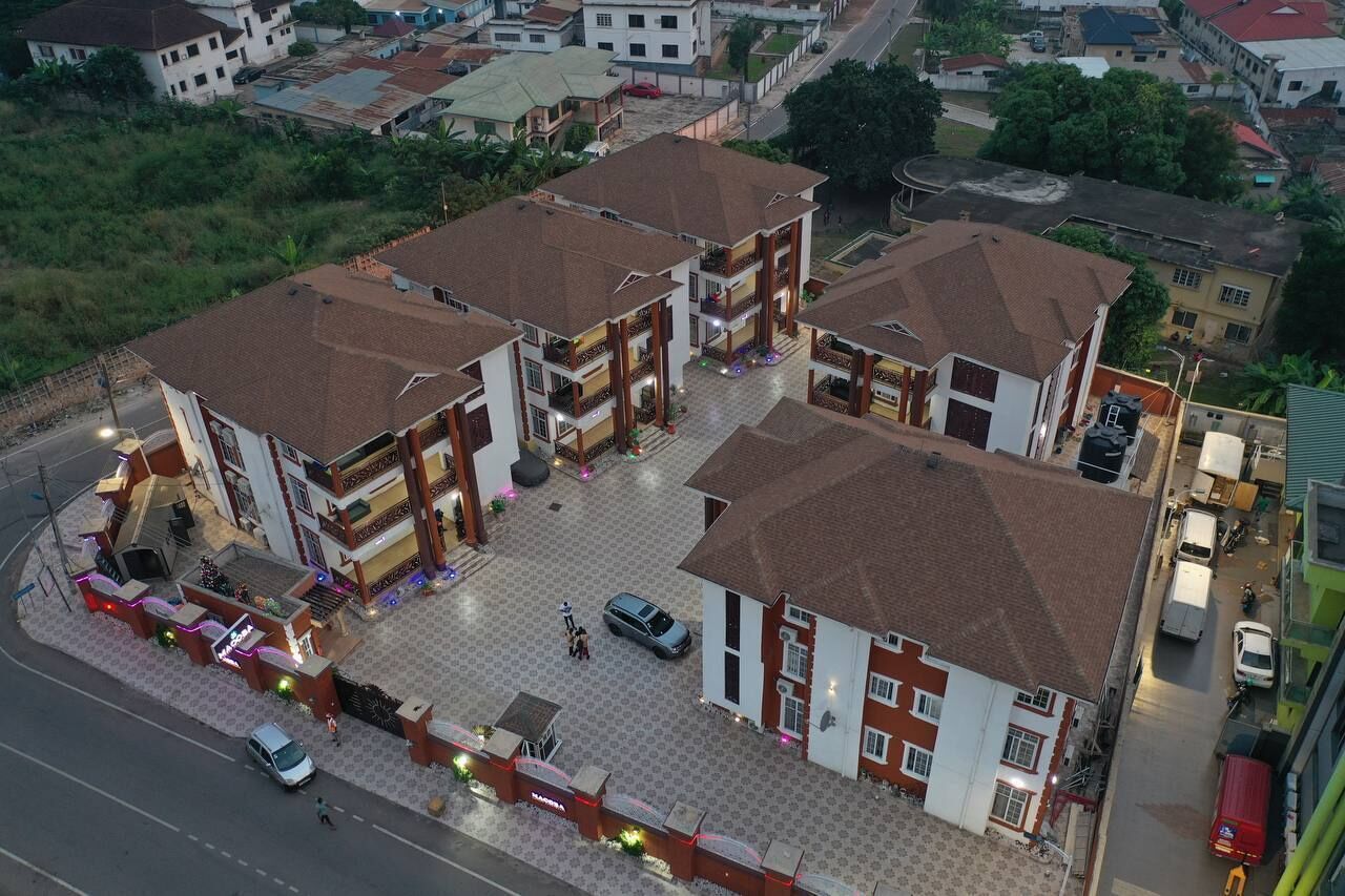 A multi-story hotel with a central courtyard, multiple balconies, and a parking area.