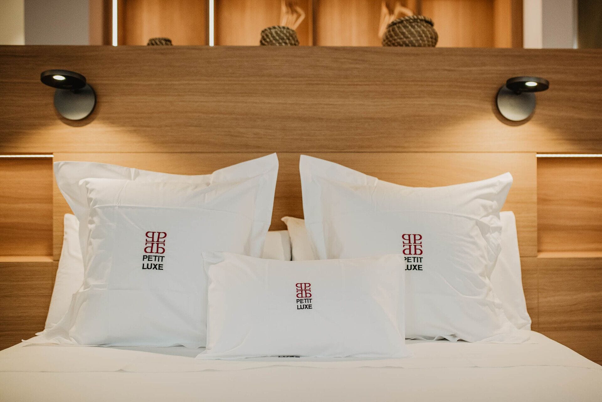 Una cama con ropa de cama y almohadas blancas que muestran un logotipo y texto.