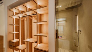A modern bathroom with a walk-in shower and a wooden shelving unit with multiple compartments. - Petit Luxe Sant Pere (Terrassa)