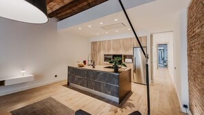 A modern kitchen with a central island, wooden cabinets, and a built-in oven. - Petit Luxe Sant Pere (Terrassa)