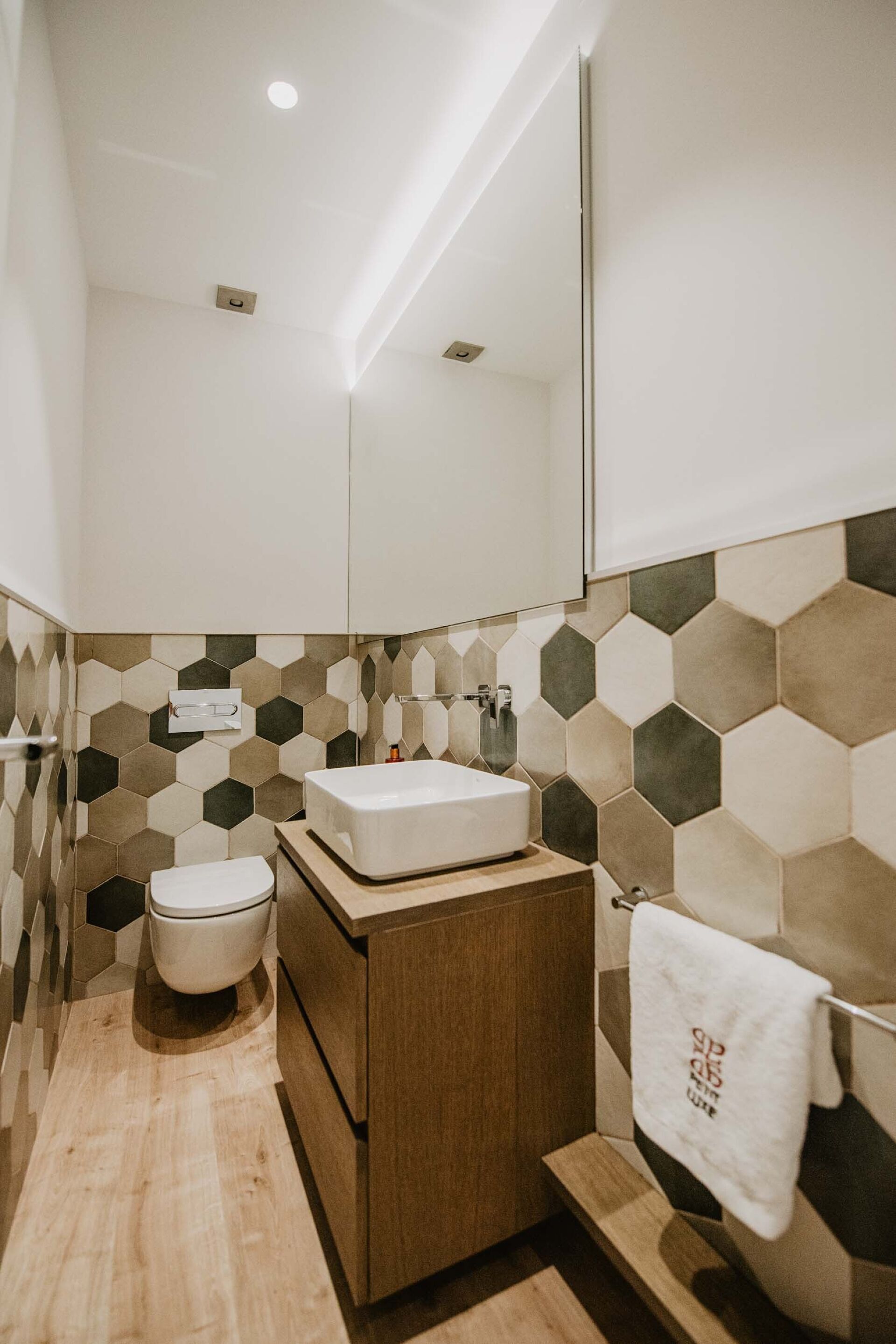 A modern bathroom with a wooden vanity, a white sink, and a toilet.