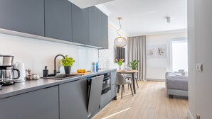 A modern kitchen with grey cabinets, a built-in oven, and a dining area with a table and chairs.