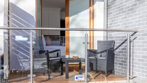 A balcony with wicker furniture, a small table, and a glass railing.