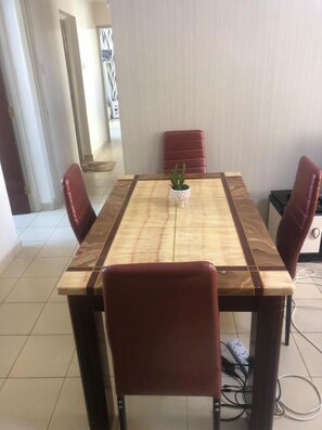 A dining area with a wooden table and four red chairs. - Stay.Plus Kahawa Sukari Apartment (Ruiru)