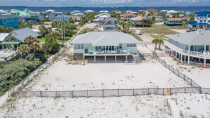 Una propiedad frente al mar con una casa grande, un patio cubierto, una piscina y vistas al océano.