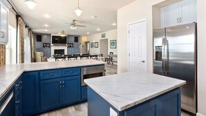 Una cocina moderna con armarios azules, un refrigerador de acero inoxidable y una encimera de mármol.