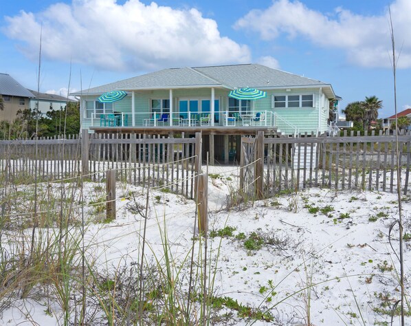 A beach house with a covered porch and a wooden fence.