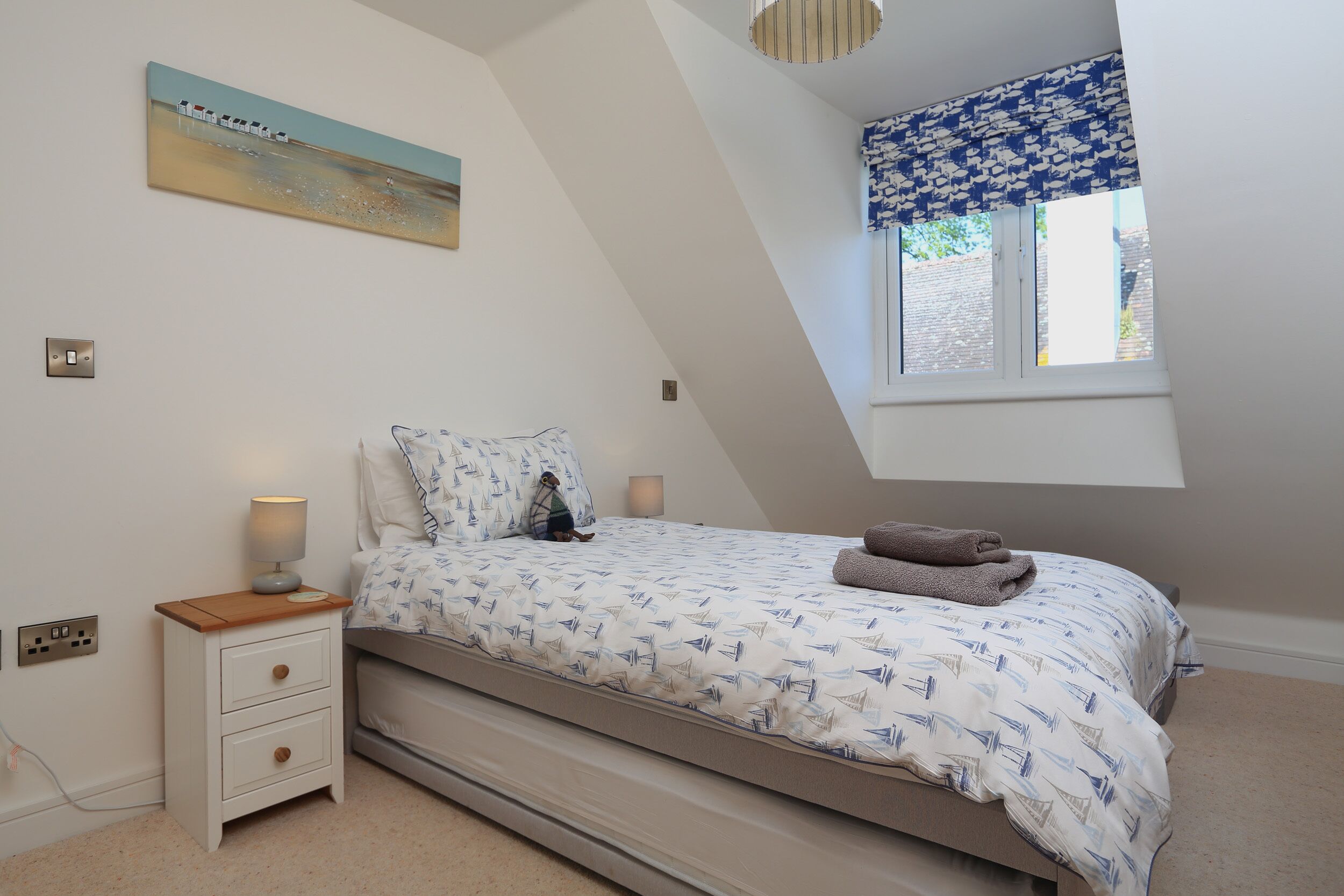 Ein Schlafzimmer mit Bett, Nachttisch, Lampe und einem Bild an der Wand.
