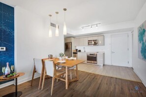 Een moderne keuken met roestvrijstalen apparatuur, een eethoek met een houten tafel en stoelen, en een grote wandkaart.
