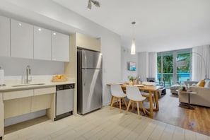 Eine moderne Küche mit weißen Schränken, einem Edelstahlkühlschrank und einem Essbereich mit Tisch und Stühlen.