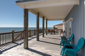 A wooden deck with chairs and tables, overlooking the ocean. - Awake On The Gulf - Gulf Front! Gaze Up At The Stars From Your Large Deck While Listening To The Waves Crash. 4 Bedroom Home by RedAwning (Dauphin Island)