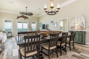 A dining area with a wooden table and chairs, a chandelier, and a large mirror.